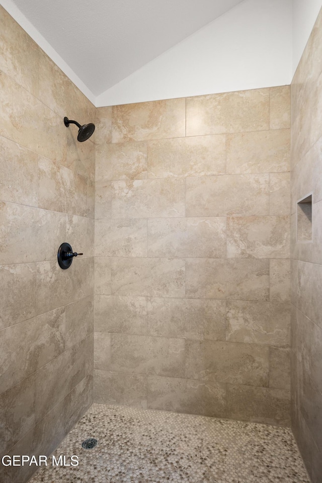 bathroom with a tile shower and vaulted ceiling