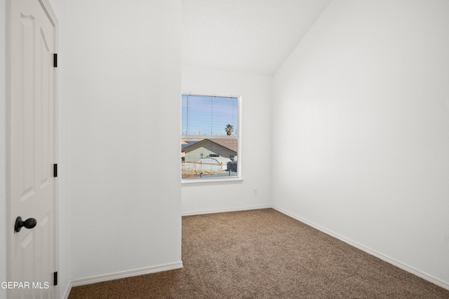 carpeted empty room with vaulted ceiling