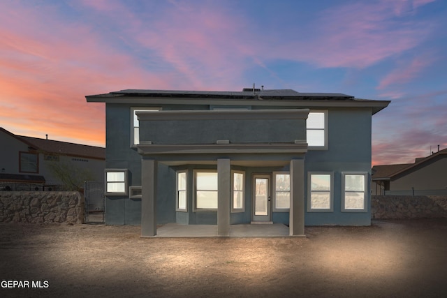 back house at dusk with a patio and solar panels