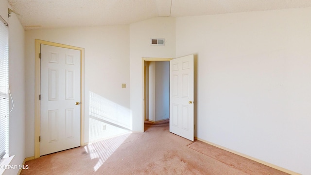 unfurnished bedroom featuring lofted ceiling and light colored carpet