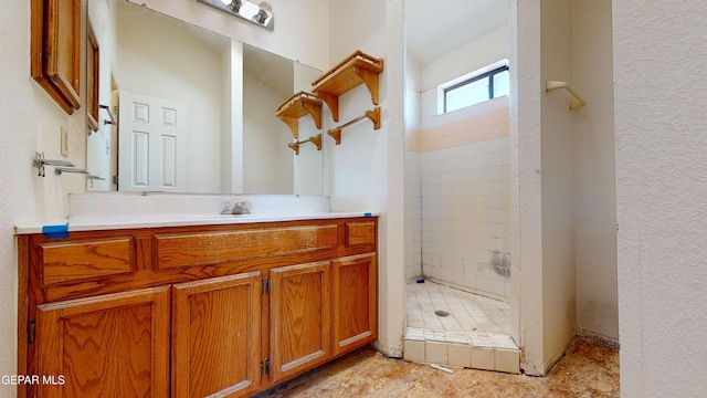 bathroom featuring tiled shower and vanity