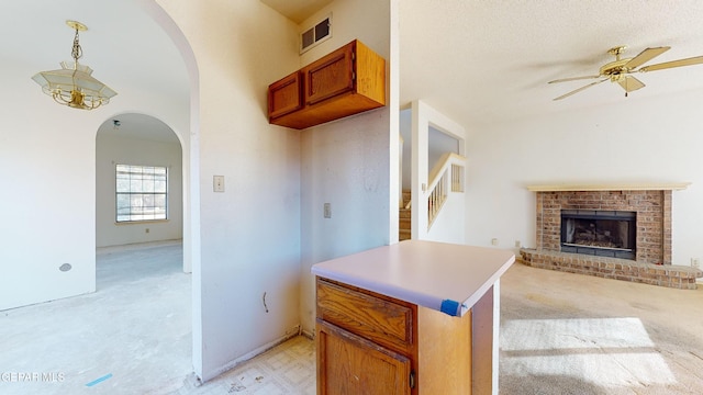 kitchen featuring decorative light fixtures, a textured ceiling, kitchen peninsula, ceiling fan, and a fireplace