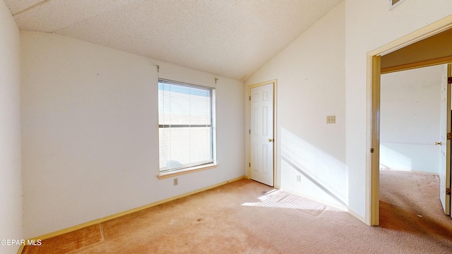 unfurnished bedroom with vaulted ceiling, light carpet, and a textured ceiling