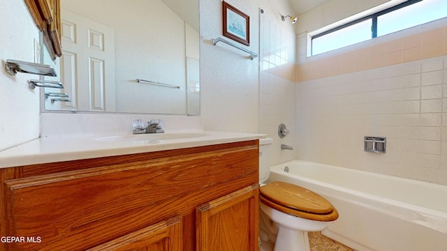 full bathroom featuring tiled shower / bath, vanity, and toilet