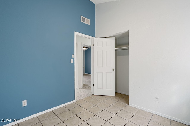 unfurnished bedroom featuring light tile patterned floors, high vaulted ceiling, and a closet