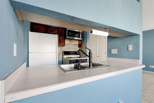 kitchen with light tile patterned flooring, sink, kitchen peninsula, white appliances, and backsplash