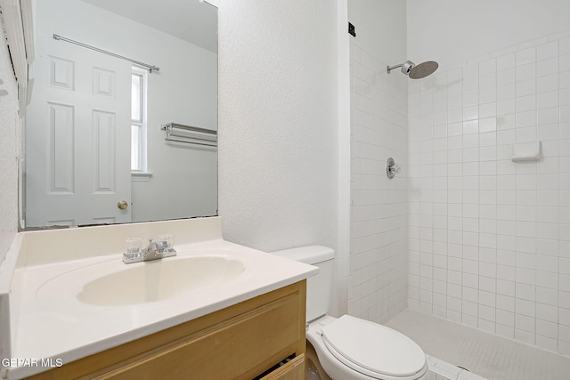 bathroom with vanity, toilet, and a tile shower