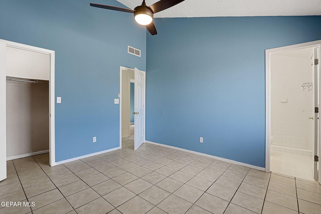 unfurnished bedroom with ceiling fan, high vaulted ceiling, a closet, and light tile patterned floors