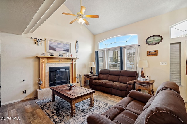 living room with ceiling fan, high vaulted ceiling, a fireplace, wood-type flooring, and a textured ceiling