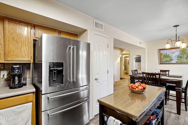 kitchen featuring pendant lighting, high end refrigerator, and an inviting chandelier