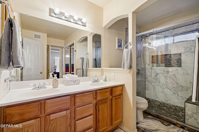 bathroom featuring vanity, toilet, and a tile shower