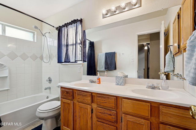 full bathroom featuring vanity, tiled shower / bath combo, and toilet