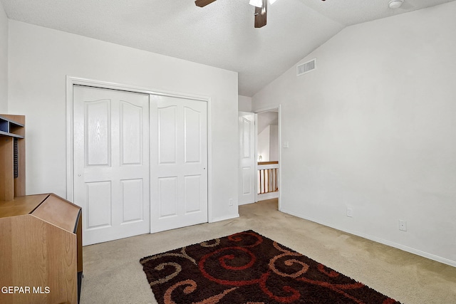 unfurnished bedroom with lofted ceiling, light carpet, a closet, and ceiling fan