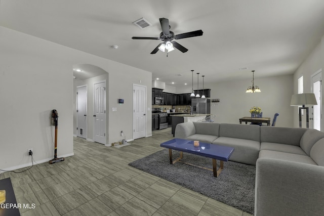 living room with sink and ceiling fan with notable chandelier