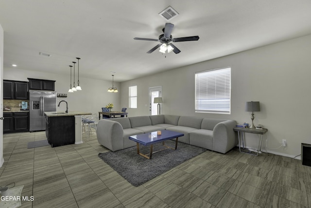 living room with sink and ceiling fan with notable chandelier