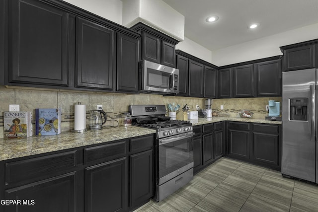 kitchen with stainless steel appliances, tasteful backsplash, and light stone counters