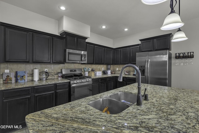 kitchen featuring appliances with stainless steel finishes, sink, decorative backsplash, hanging light fixtures, and light stone countertops