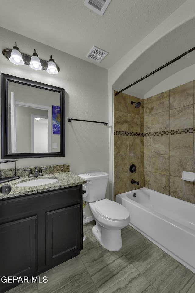 full bathroom featuring vanity, tiled shower / bath combo, a textured ceiling, and toilet