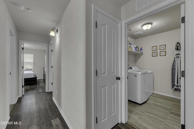 clothes washing area featuring wood-type flooring and washing machine and dryer