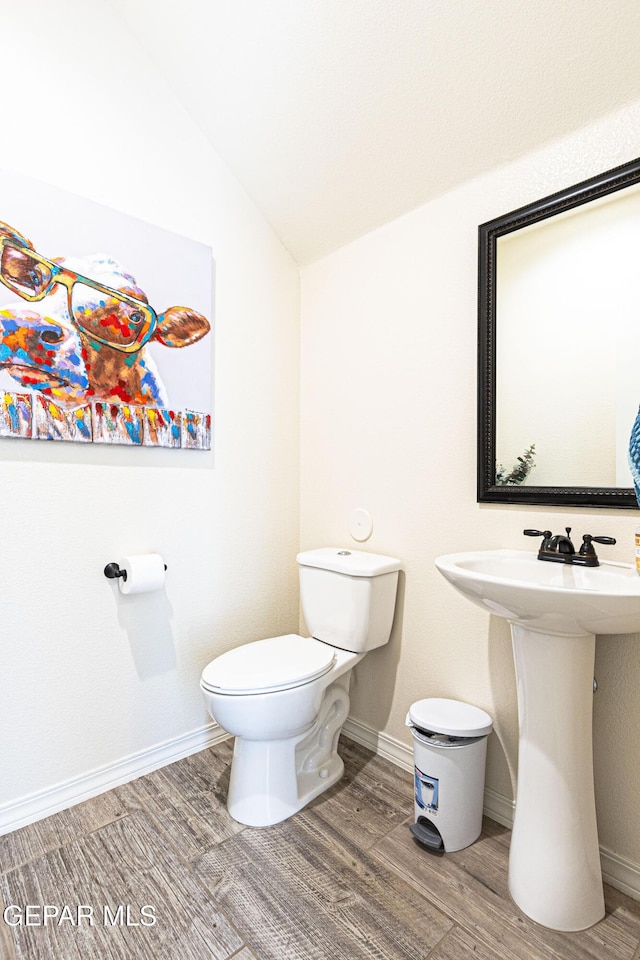 bathroom with lofted ceiling, hardwood / wood-style floors, and toilet