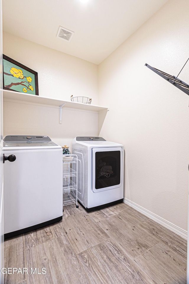 laundry area with washer and dryer and light hardwood / wood-style floors