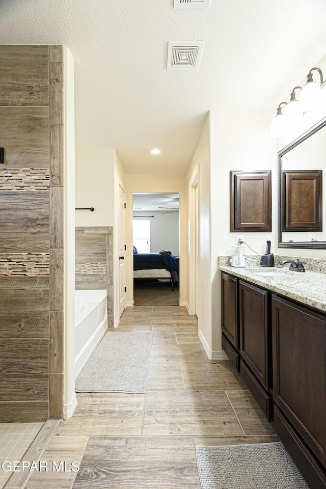 bathroom with vanity, hardwood / wood-style floors, a textured ceiling, and a bathtub