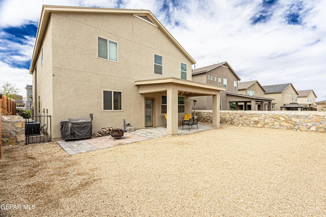 rear view of house featuring a fire pit, a patio area, and central air condition unit