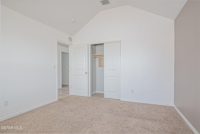 unfurnished bedroom featuring vaulted ceiling, a closet, and carpet