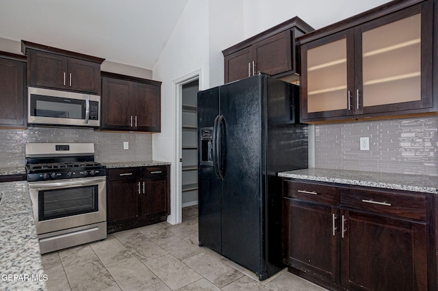 kitchen featuring light stone countertops, dark brown cabinets, stainless steel appliances, and vaulted ceiling