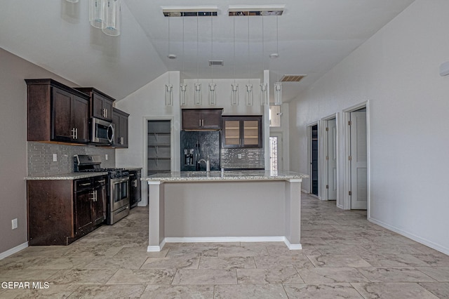 kitchen featuring pendant lighting, dark brown cabinets, a center island with sink, and appliances with stainless steel finishes