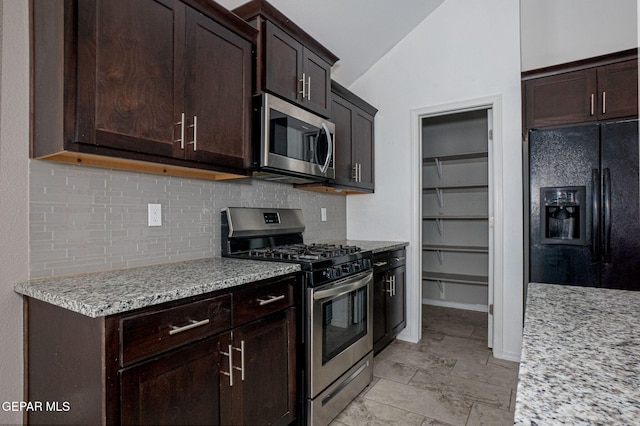 kitchen featuring lofted ceiling, dark brown cabinets, stainless steel appliances, light stone countertops, and decorative backsplash