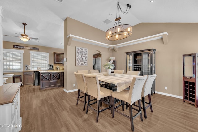 dining room with lofted ceiling, ceiling fan with notable chandelier, and light hardwood / wood-style floors