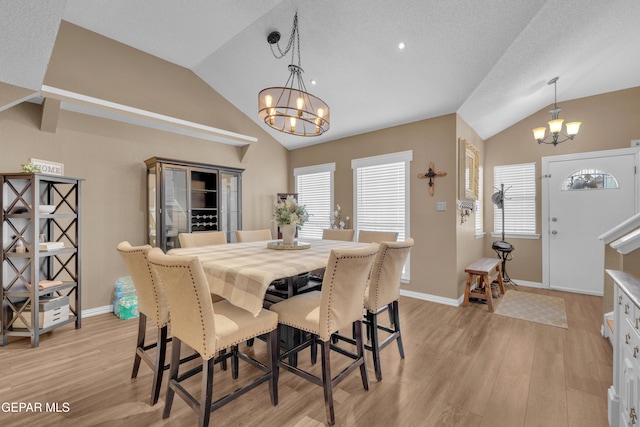 dining area featuring vaulted ceiling, a wealth of natural light, a chandelier, and light hardwood / wood-style floors