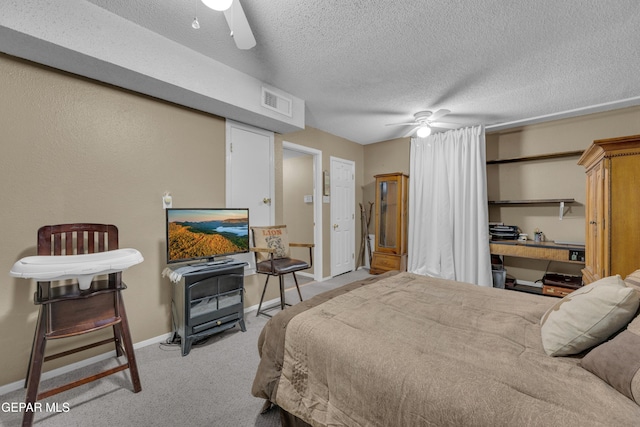 carpeted bedroom featuring ceiling fan and a textured ceiling