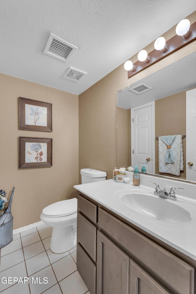 bathroom featuring tile patterned floors, vanity, toilet, and a textured ceiling