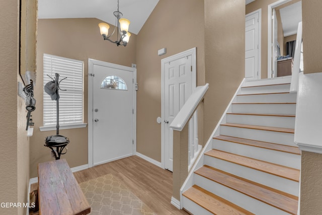 foyer featuring an inviting chandelier, vaulted ceiling, and light wood-type flooring