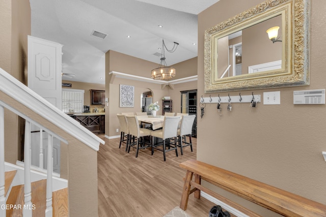 dining space with lofted ceiling, a notable chandelier, and light hardwood / wood-style floors