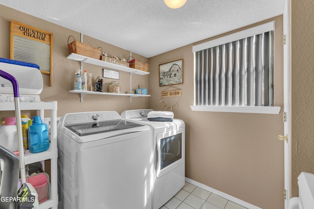 clothes washing area featuring light tile patterned flooring, washer and dryer, and a textured ceiling