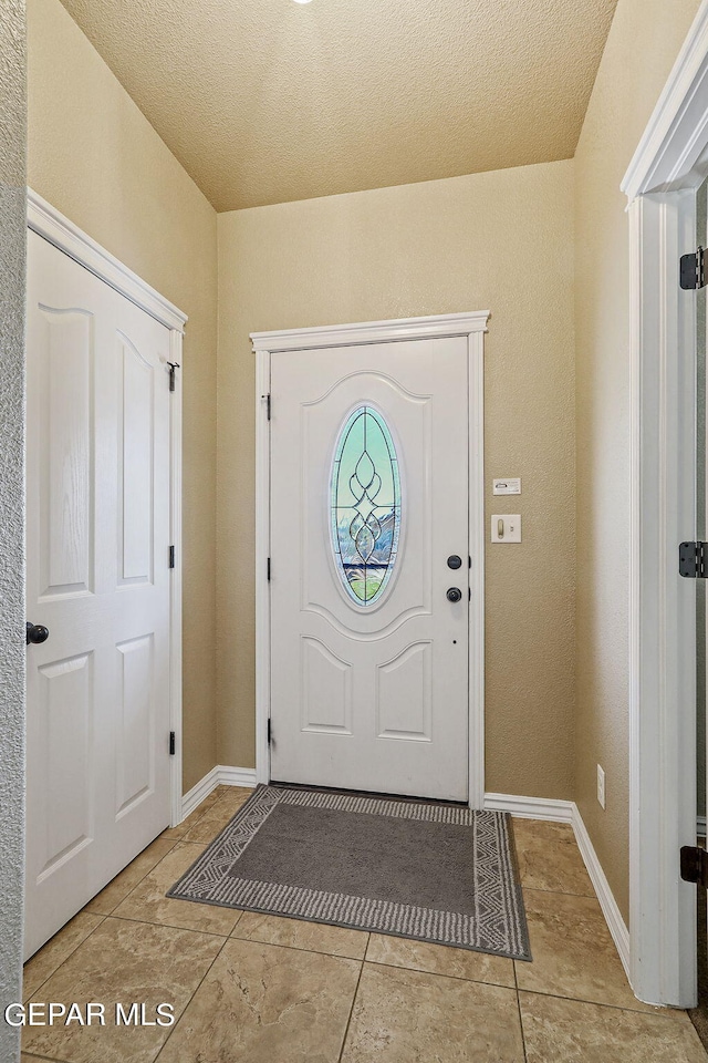 tiled entryway with a textured ceiling