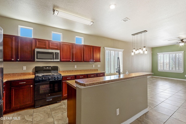 kitchen featuring light tile patterned floors, a center island, gas stove, a textured ceiling, and decorative light fixtures