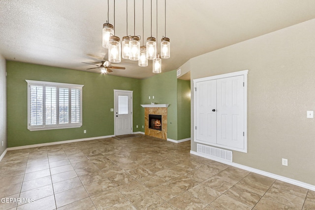 unfurnished living room with ceiling fan, a fireplace, and a textured ceiling