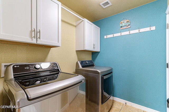 laundry room with washing machine and dryer, cabinets, and light tile patterned flooring