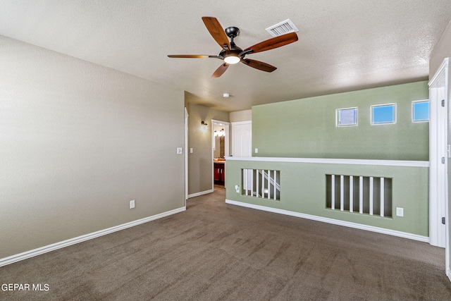 unfurnished room featuring ceiling fan, a textured ceiling, and dark colored carpet