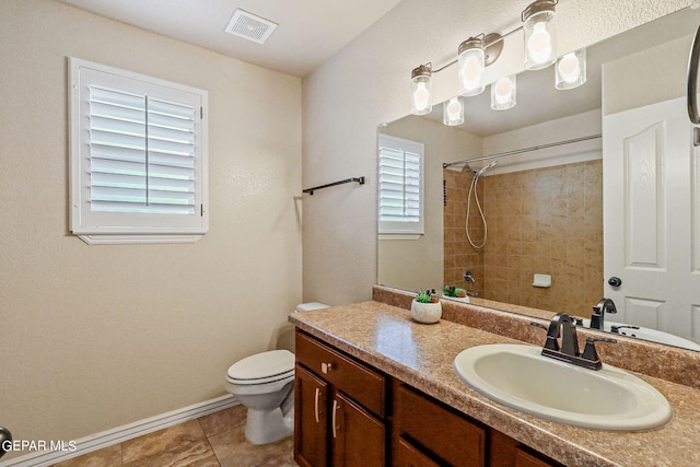 bathroom with vanity, tile patterned flooring, toilet, and a tile shower