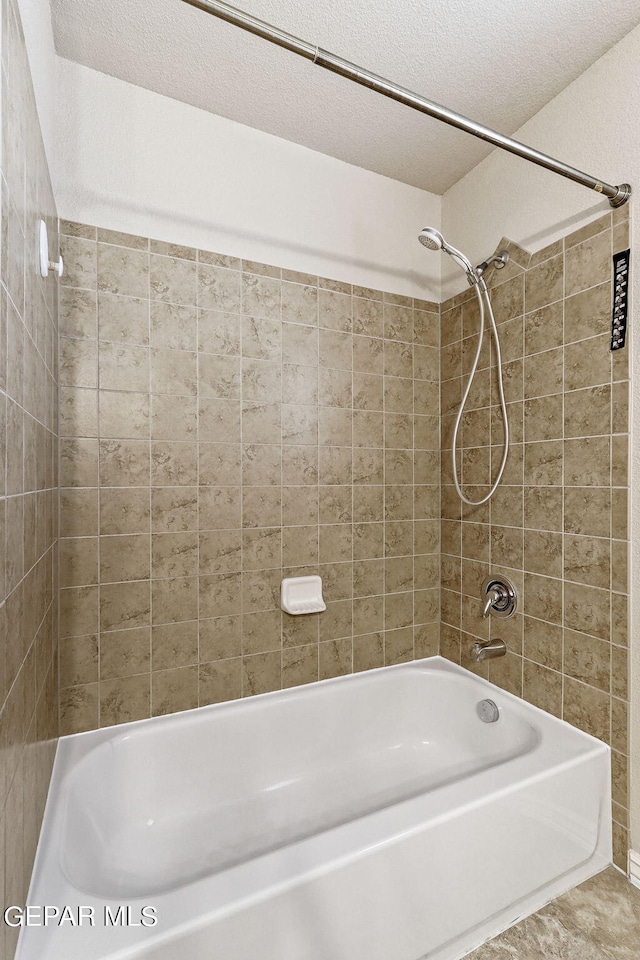 bathroom with tiled shower / bath and a textured ceiling