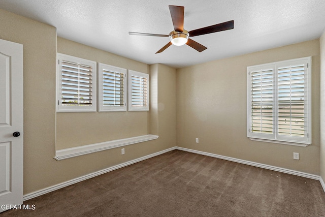 spare room with ceiling fan, dark carpet, a textured ceiling, and a healthy amount of sunlight