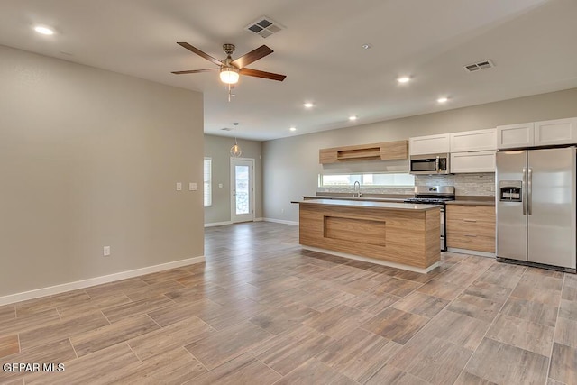 kitchen with tasteful backsplash, sink, white cabinets, ceiling fan, and stainless steel appliances