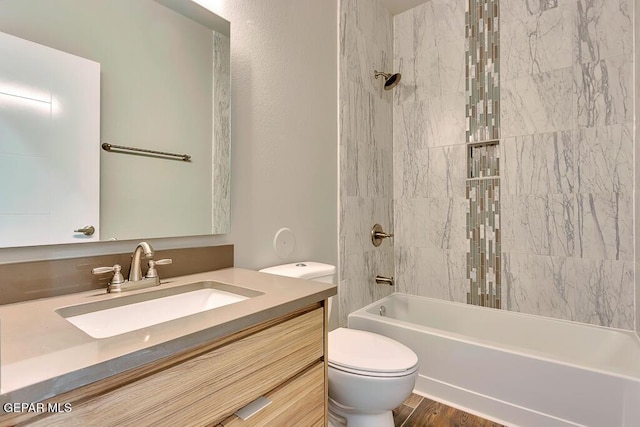 full bathroom with tiled shower / bath, hardwood / wood-style floors, vanity, and toilet