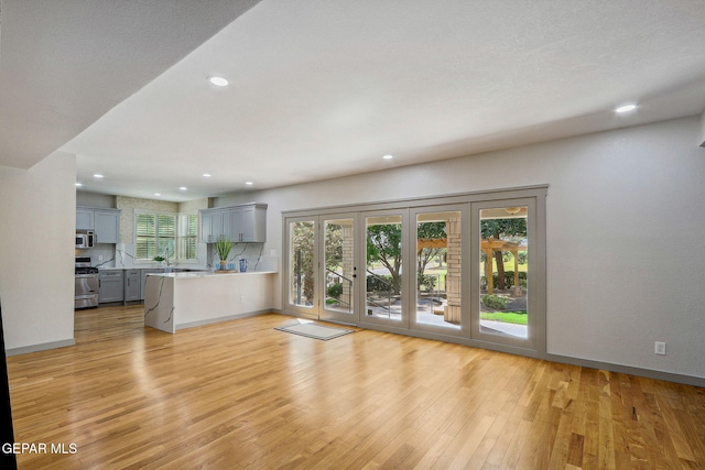 909 Singing Hills Dr, El Paso, TX 79912 - unfurnished living room featuring light wood-style flooring, recessed lighting, and baseboards