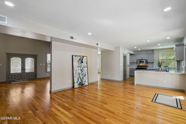 909 Singing Hills Dr, El Paso, TX 79912 - unfurnished living room with light wood finished floors, recessed lighting, baseboards, and french doors